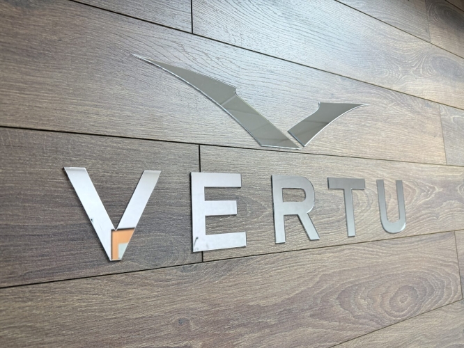 Вывеска VERTU из зеркального акрила на деревянной стене — резка и монтаж Sunprint